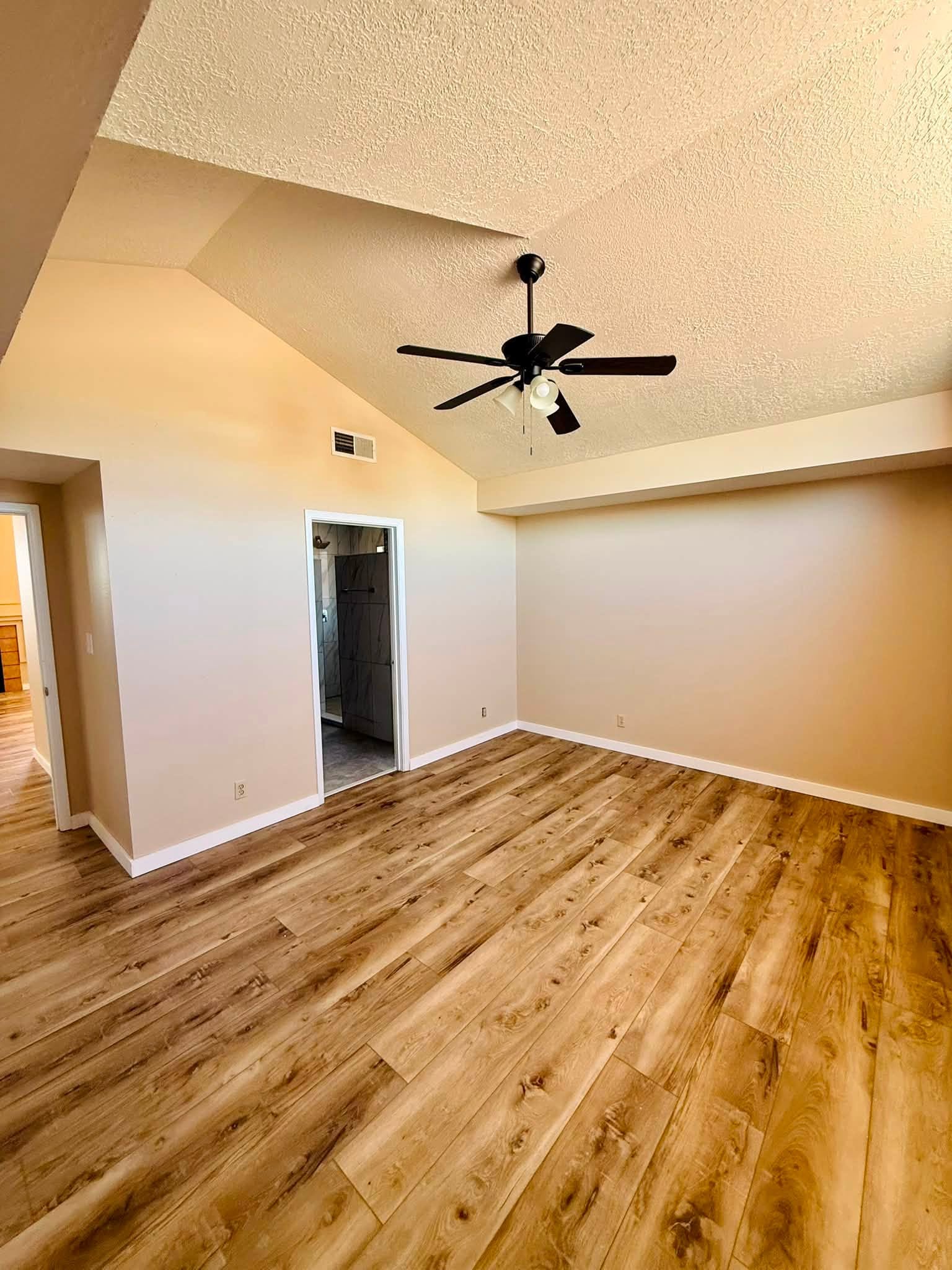 Completed interior painting with warm neutral walls, white trim, and a vaulted ceiling